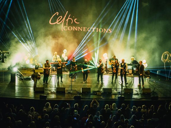 A band perform on stage, in front of a Celtic Connections sign.
